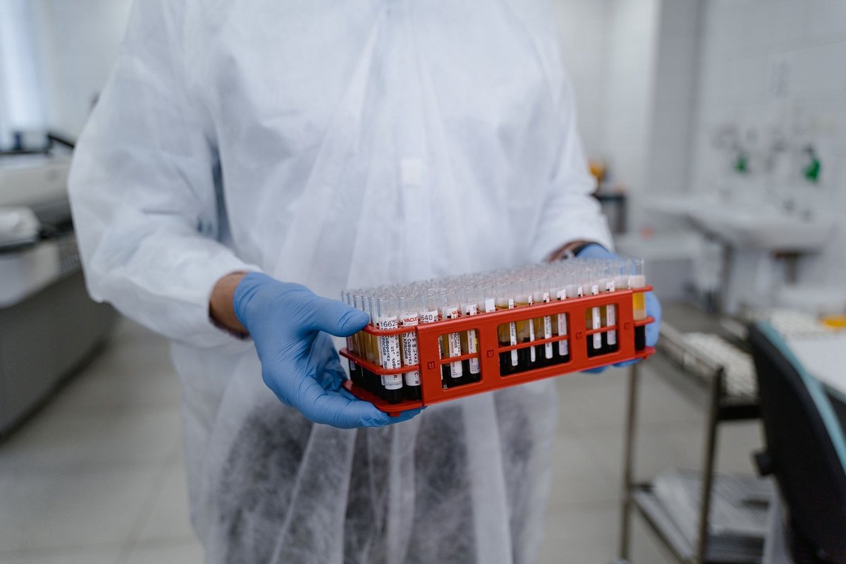 Scientifique manipulant un plateau rouge de tubes à essai dans un laboratoire Scientifique manipulant un plateau rouge de tubes à essai dans un laboratoire
