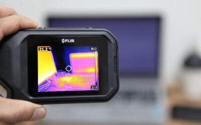 Une main tient un appareil thermique FLIR affichant la carte de chaleur d'un ordinateur