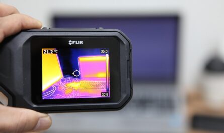 Une main tient un appareil thermique FLIR affichant la carte de chaleur d'un ordinateur
