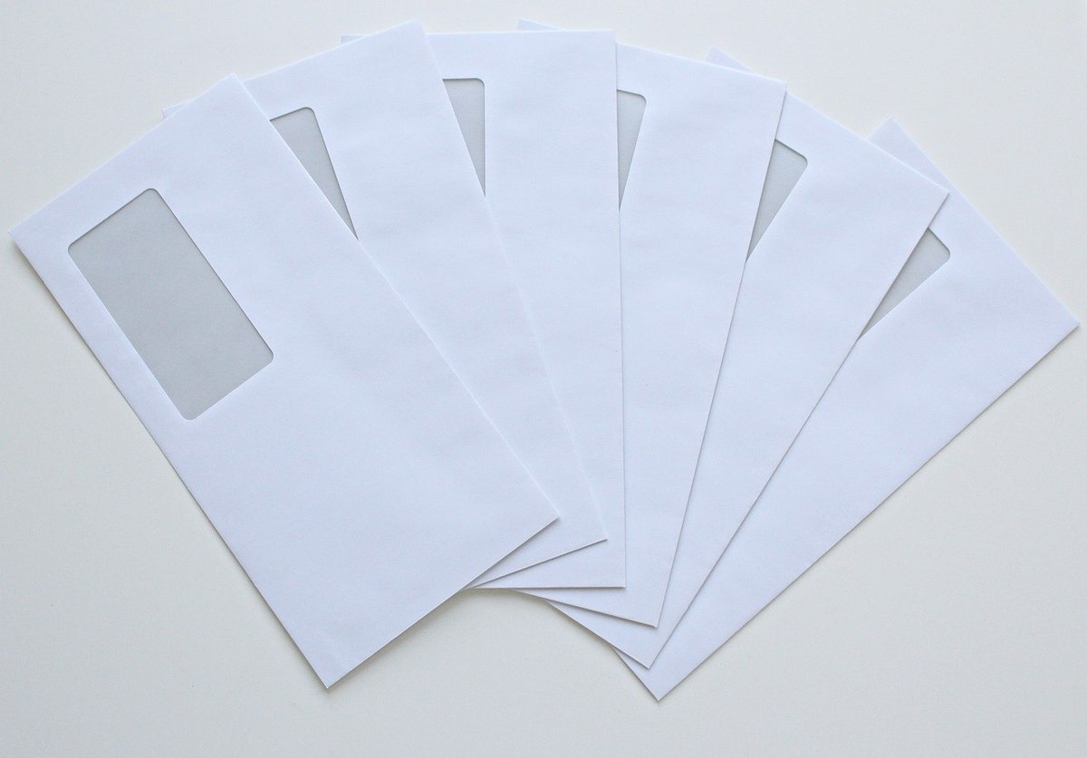 Plusieurs enveloppes blanches à fenêtre transparente disposées en éventail Plusieurs enveloppes blanches à fenêtre transparente disposées en éventail