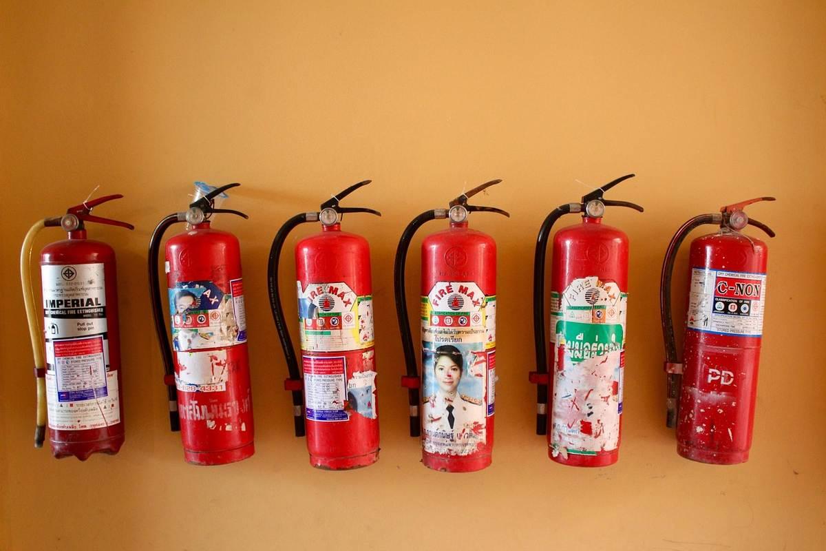 Six extincteurs rouges sur un mur orangé Six extincteurs rouges sur un mur orangé